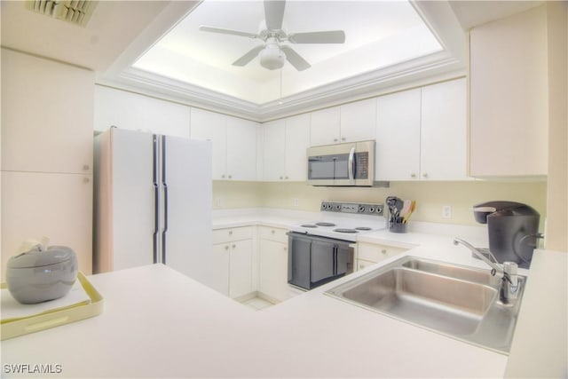 kitchen with white appliances, a sink, white cabinetry, light countertops, and a tray ceiling