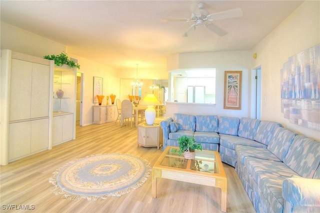 living area featuring ceiling fan with notable chandelier and light wood-style flooring