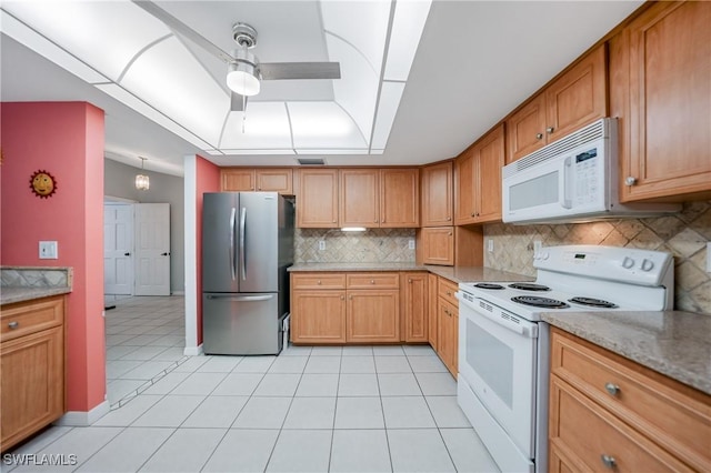 kitchen with light tile patterned floors, white appliances, light stone counters, and backsplash