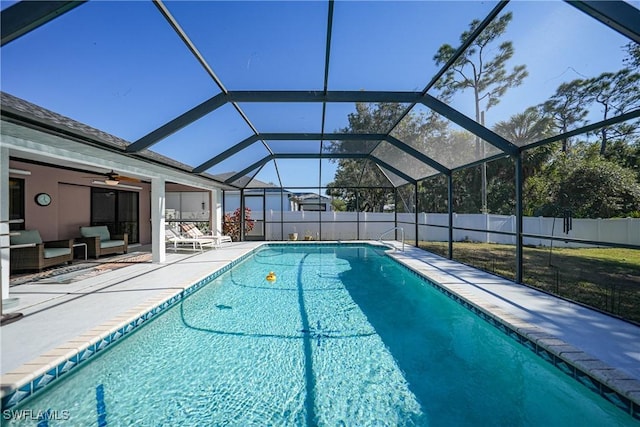 view of pool with outdoor lounge area, glass enclosure, ceiling fan, and a patio area