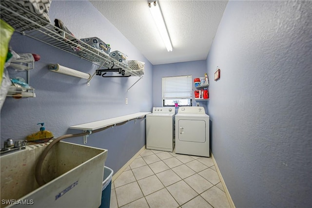 laundry area with washer and clothes dryer, sink, light tile patterned flooring, and a textured ceiling