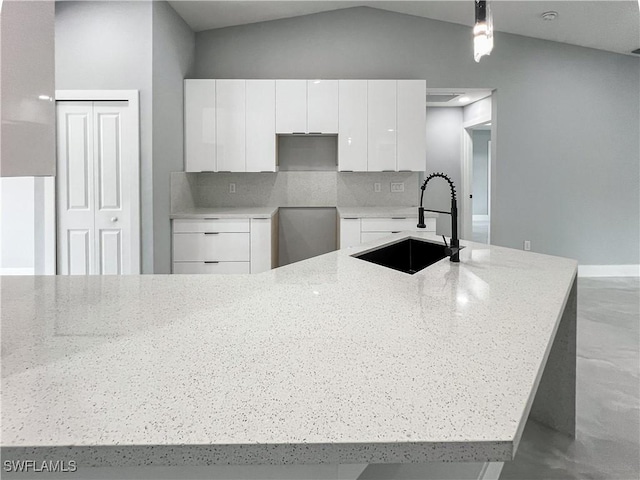 kitchen featuring white cabinetry, sink, backsplash, vaulted ceiling, and decorative light fixtures