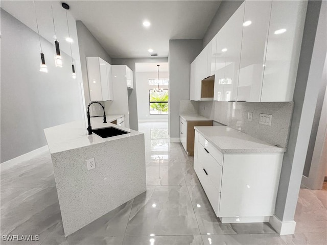 kitchen featuring tasteful backsplash, sink, pendant lighting, a notable chandelier, and white cabinets