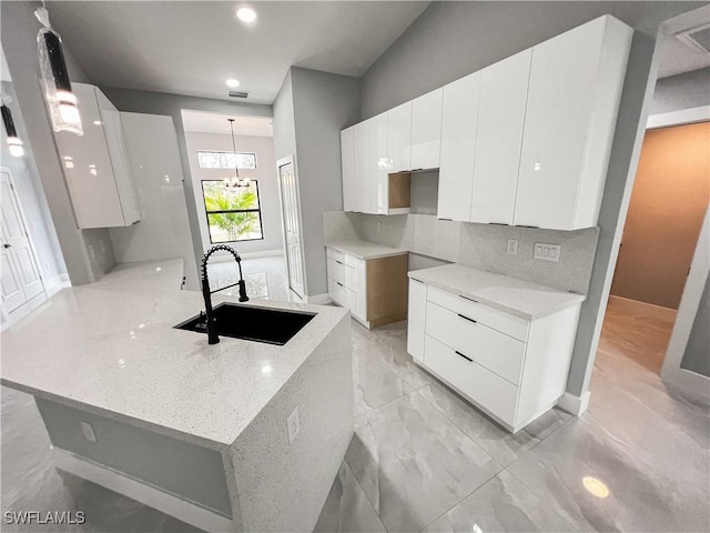 kitchen featuring white cabinets, an inviting chandelier, hanging light fixtures, and sink