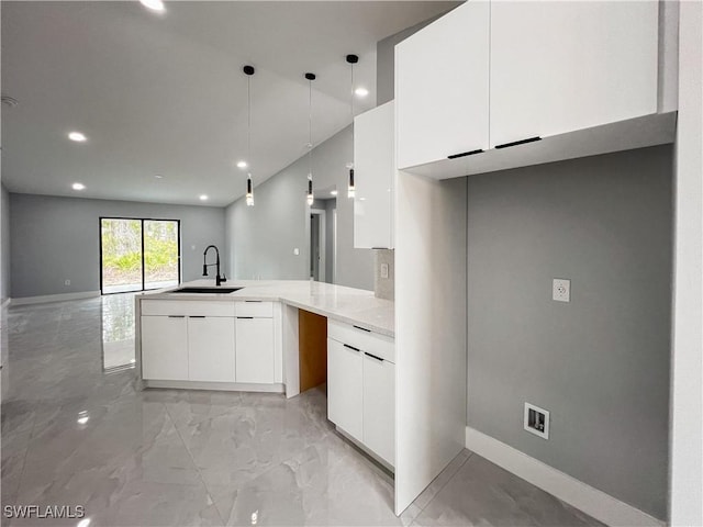 kitchen with kitchen peninsula, sink, white cabinets, and decorative light fixtures