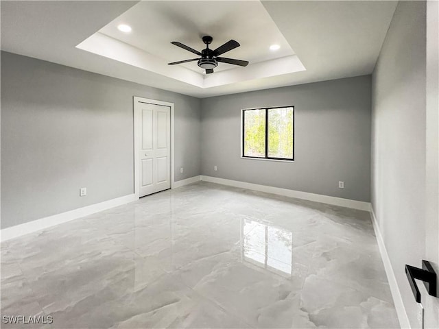 unfurnished room featuring a raised ceiling and ceiling fan