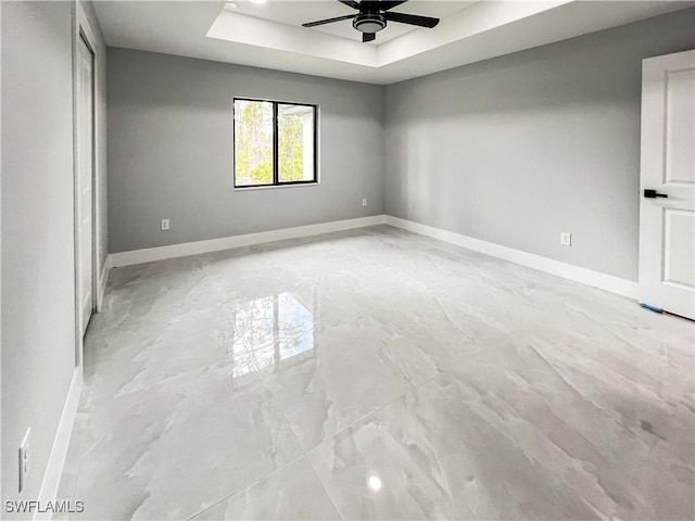 spare room featuring ceiling fan and a raised ceiling