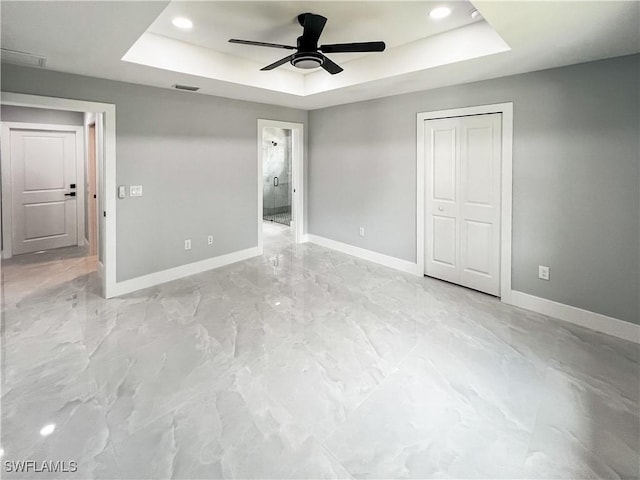 unfurnished bedroom with a closet, a raised ceiling, and ceiling fan