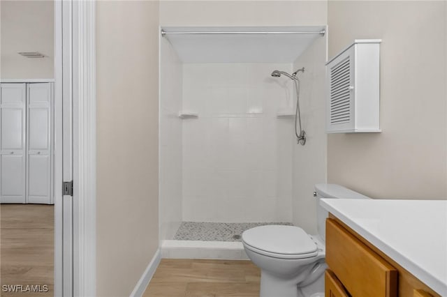 bathroom featuring tiled shower, hardwood / wood-style floors, vanity, and toilet