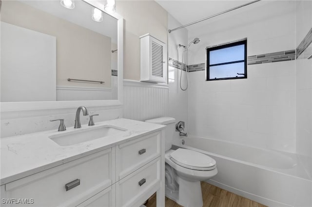 full bathroom featuring vanity, wood-type flooring, tiled shower / bath combo, and toilet