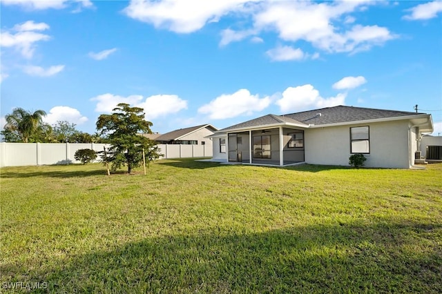 rear view of property featuring a lawn, central AC, and a sunroom