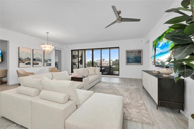 living room with ceiling fan with notable chandelier and light wood finished floors