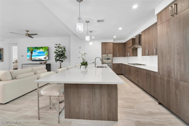 kitchen featuring wall chimney range hood, modern cabinets, a breakfast bar area, and light countertops