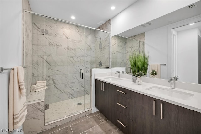 bathroom featuring visible vents, a sink, a shower stall, and double vanity