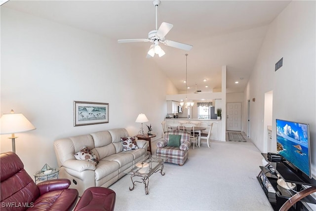 carpeted living room with ceiling fan and high vaulted ceiling