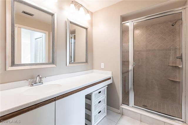 bathroom with walk in shower, vanity, and tile patterned floors