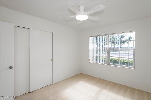 unfurnished bedroom with light carpet, a closet, and ceiling fan