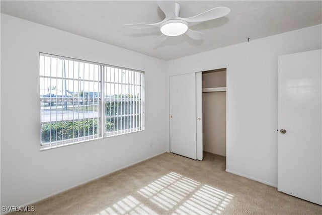 unfurnished bedroom with ceiling fan, light carpet, and a closet