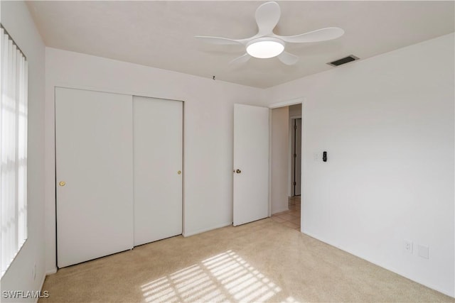 unfurnished bedroom with light carpet, a closet, and ceiling fan