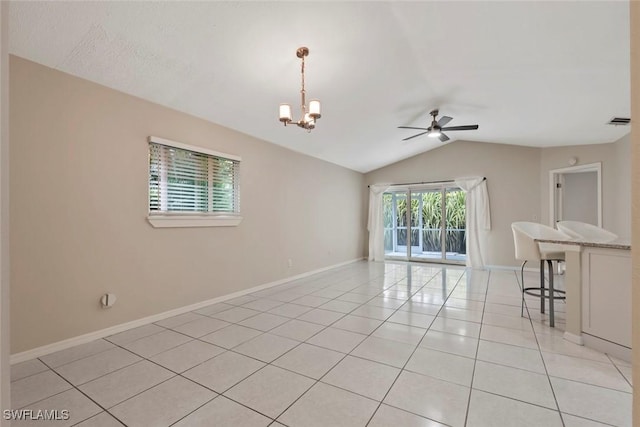 spare room featuring ceiling fan with notable chandelier, light tile patterned flooring, and lofted ceiling