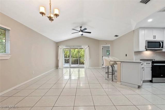 kitchen with white cabinets, light stone counters, lofted ceiling, and stainless steel appliances