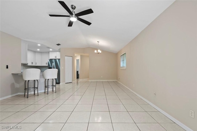 tiled living room with ceiling fan with notable chandelier and vaulted ceiling