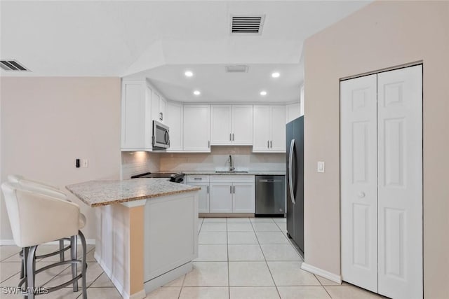 kitchen featuring white cabinetry, sink, stainless steel appliances, a kitchen breakfast bar, and kitchen peninsula