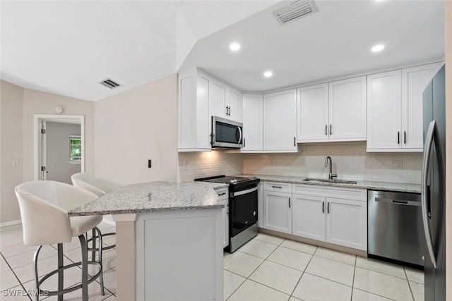 kitchen featuring white cabinetry, sink, stainless steel appliances, kitchen peninsula, and a breakfast bar area