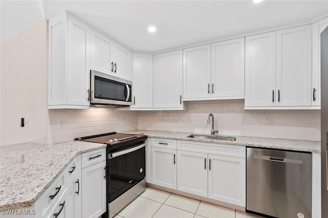 kitchen featuring white cabinets, sink, decorative backsplash, appliances with stainless steel finishes, and light tile patterned flooring