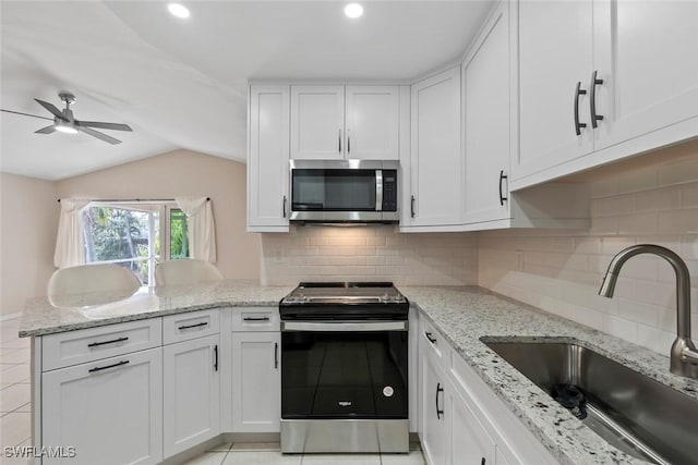 kitchen featuring appliances with stainless steel finishes, white cabinetry, lofted ceiling, and sink