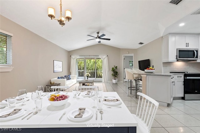 tiled dining area featuring ceiling fan with notable chandelier and vaulted ceiling