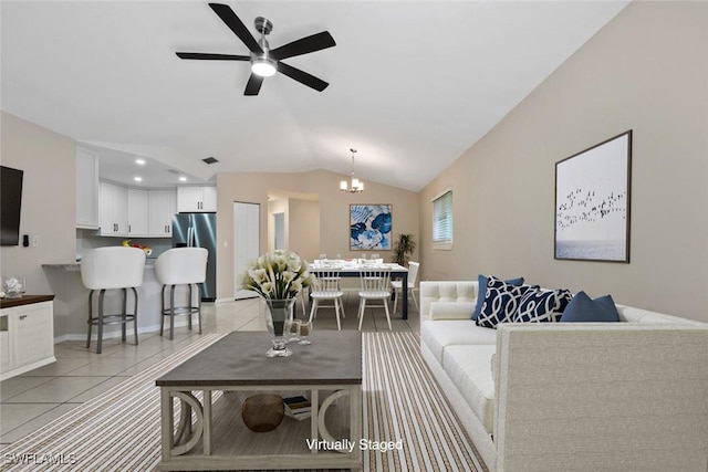 living room with ceiling fan with notable chandelier, light tile patterned floors, and lofted ceiling