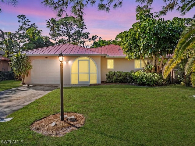 view of front of property with a garage and a yard