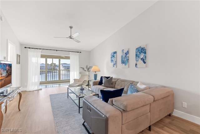 living room with lofted ceiling, light hardwood / wood-style flooring, ceiling fan, and a water view