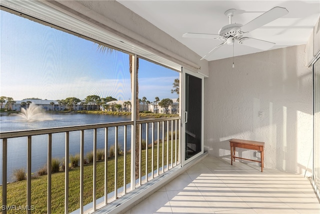 sunroom with ceiling fan and a water view