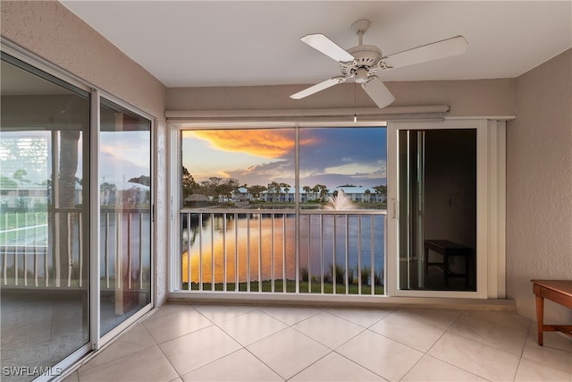 unfurnished sunroom featuring ceiling fan and a water view