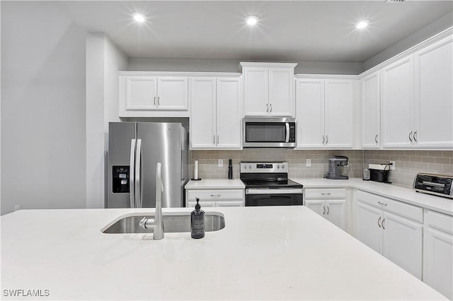 kitchen with appliances with stainless steel finishes, white cabinetry, and tasteful backsplash