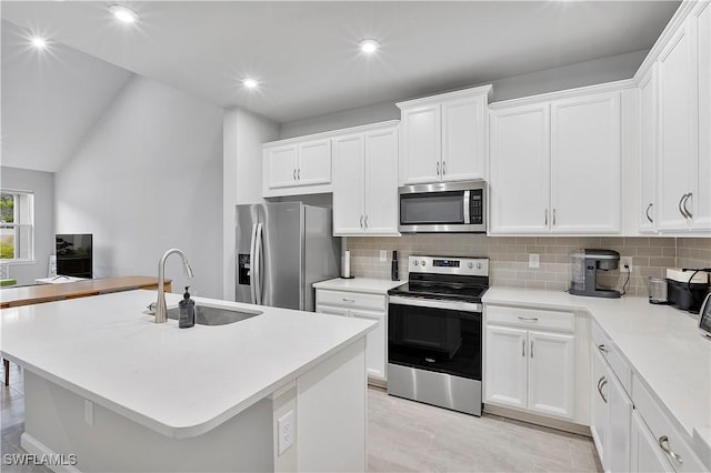 kitchen featuring decorative backsplash, sink, white cabinetry, appliances with stainless steel finishes, and an island with sink