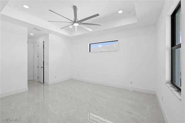 spare room featuring a tray ceiling and ceiling fan