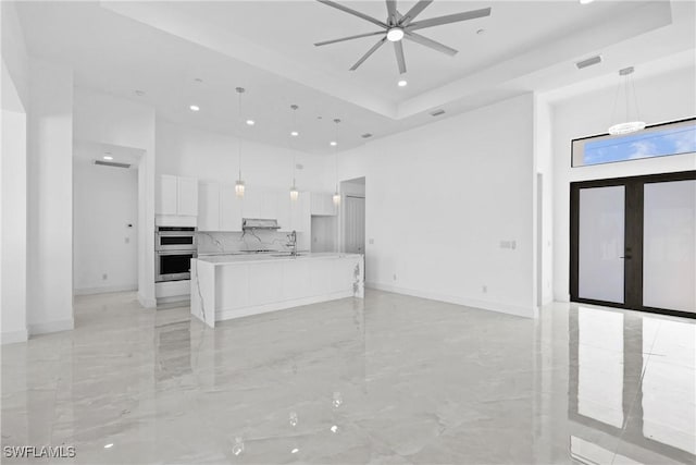 kitchen featuring a spacious island, hanging light fixtures, ceiling fan, double oven, and white cabinetry