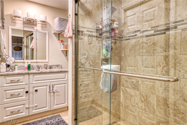 bathroom featuring a shower with door and vanity