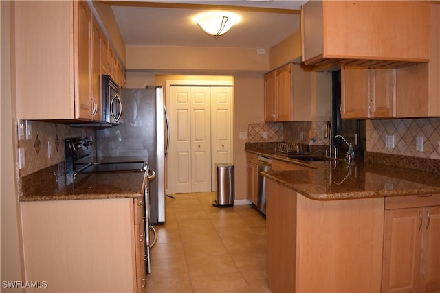 kitchen featuring stainless steel appliances, sink, tasteful backsplash, kitchen peninsula, and dark stone counters