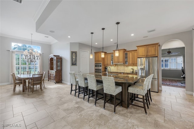 dining space featuring ceiling fan with notable chandelier, a healthy amount of sunlight, ornamental molding, and sink