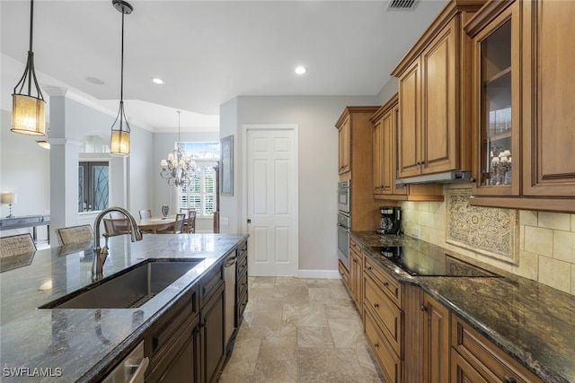 kitchen featuring black electric cooktop, sink, decorative light fixtures, dark stone countertops, and a chandelier