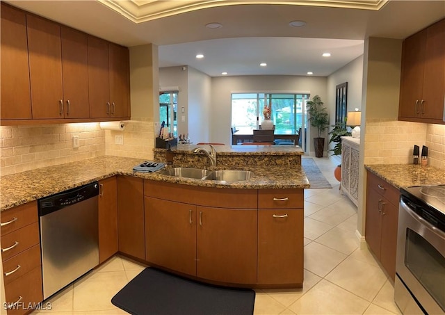 kitchen featuring kitchen peninsula, appliances with stainless steel finishes, light stone countertops, and sink