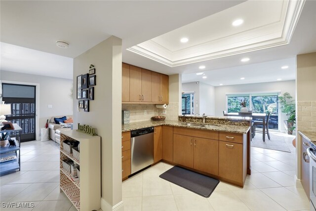 kitchen featuring sink, stainless steel dishwasher, a tray ceiling, kitchen peninsula, and light stone countertops