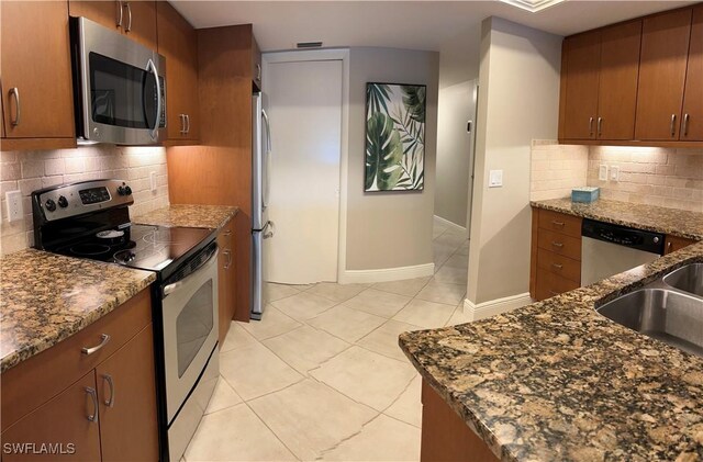 kitchen with light tile patterned floors, stainless steel appliances, and dark stone counters