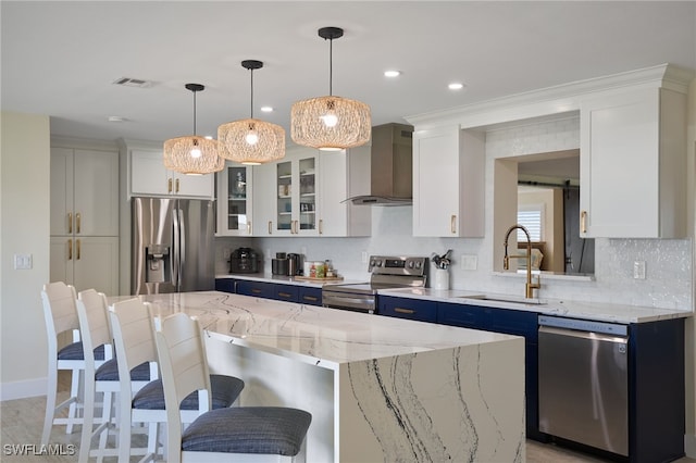 kitchen with sink, white cabinetry, stainless steel appliances, a center island, and wall chimney exhaust hood