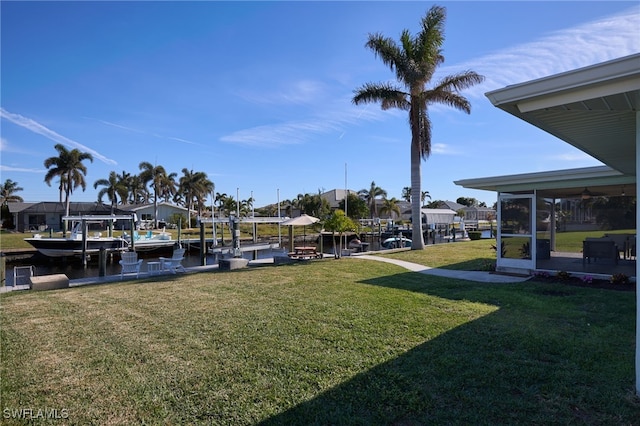 view of yard with a water view, a sunroom, and a boat dock