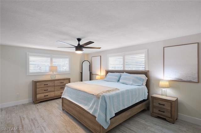 bedroom with multiple windows, light hardwood / wood-style flooring, and ceiling fan